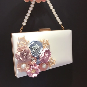 Close-up of white bridal clutch bag with 3D floral petals and pearl handle detail