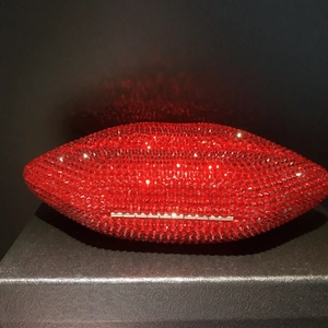 Detailed view of red lip-shaped evening clutch bag encrusted with shimmering crystals