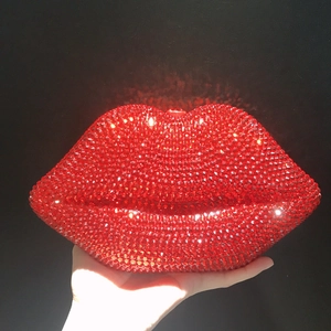Close-up of red rhinestone-encrusted lip-shaped clutch bag held in hand for parties