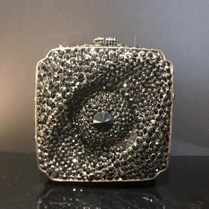 Vue détaillée d'une pochette carrée de luxe avec strass noirs et cristal central