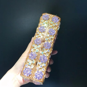 Close-up of purple rhinestones flower pattern on a golden metallic evening clutch bag