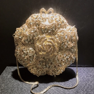 Macro detail of champagne gold rose evening bag with hand-set crystals and metal chain