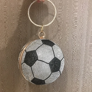 Detail of football-shaped evening bag with black and white rhinestones and gold ring handle
