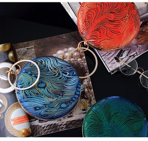 Detail view of round peacock feather texture bags with luxury diamond ring handles