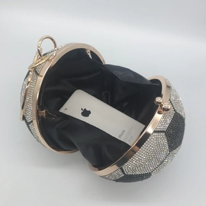 Detailed interior view of a soccer-shaped rhinestone clutch with a smartphone for scale
