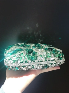 Detailed close-up of emerald green and clear crystal rhinestones on luxury evening clutch