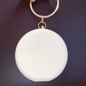 Pochette ronde blanche en cuir avec poignée anneau doré et détail fleur de soleil en diamants