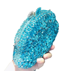 Blue rhinestone evening clutch bag with crystal floral clasp held against white background