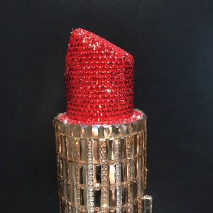 Vue détaillée du sac pochette rouge et or en forme de rouge à lèvres serti de strass