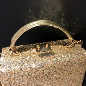 Elegant gold sequin handbag with luxury woven handle and metallic square lock closure
