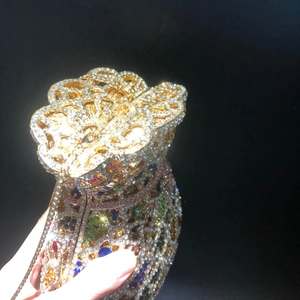 Vue détaillée de la pochette dorée ajourée ornée de strass multicolores brillants