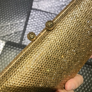 Elegant gold evening clutch bag covered in sparkling rhinestones with a metal frame