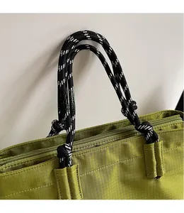 Détail du sac fourre-tout vert avec poignée en corde tissée noir et blanc et maille