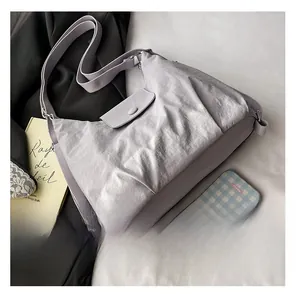 Detail view of a large lilac nylon crossbody bag featuring a flap closure and wide strap