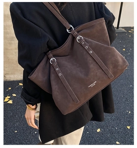 Detailed side view of large dark brown suede tote bag with silver buckle on a model