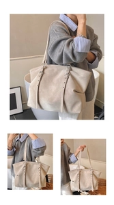 Detail view of large beige tote bag with decorative side buckles and silver metal rings