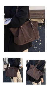 Detail of dark brown suede tote bag featuring silver metal rings and hanging strap decoration
