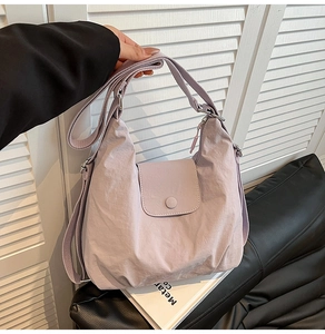 Detail der hellvioletten Nylon-Hobo-Tasche mit verstellbarem Gurt vor schlichtem Dekor