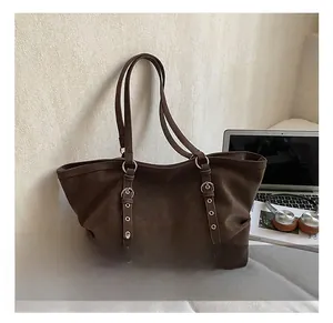 Close-up of brown suede tote bag featuring silver ring hardware and long adjustable straps