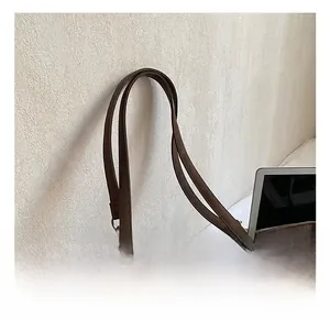 Detail showing the coffee brown tote bag with slim shoulder strap and leather texture
