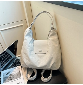 Detailansicht der cremefarbenen Hobo-Tasche mit strukturierter Textur und Druckknopfverschluss