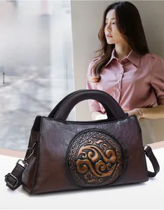 Detail of vintage embossed pattern on brown faux leather handbag with top handle and strap