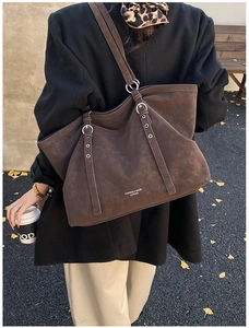 Détail du grand sac cabas en daim marron avec boucles argentées et logo imprimé élégant