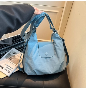 Hellblaue Nylon-Umhängetasche mit breitem Gurt und Klappenverschluss im Lifestyle-Ambiente