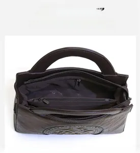 Detail view of the brown embossed shoulder bag featuring three zipper compartments