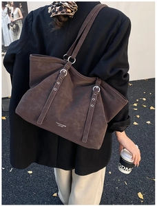 Detail of dark brown leather tote bag showing silver metal ring and adjustable strap