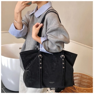Détail d'un grand sac cabas noir en daim avec boucles en métal argenté