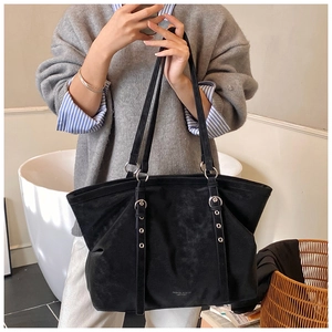 Detail of black matte tote bag featuring decorative silver eyelet straps and branding