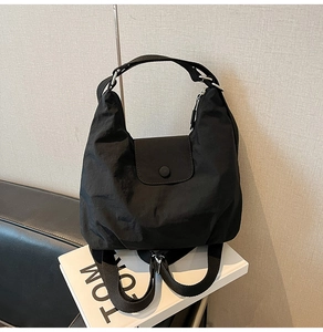 Detail of black nylon tote bag showing wrinkled fabric texture and metal snap closure