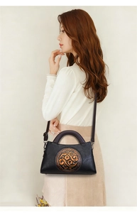 Detail view of vintage black embossed bag with bronze floral medallion and leather texture