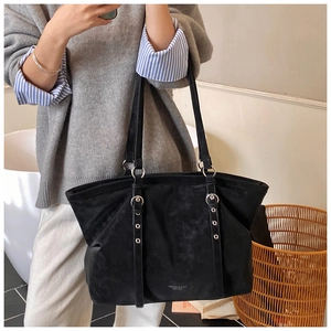 Detail of black suede tote bag featuring silver metal rings and embossed fashion logo