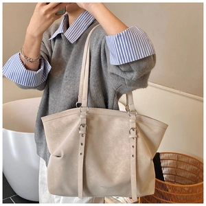 Detail of a creamy white leather tote bag with adjustable metal eyelet straps and logo