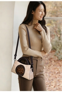Detail view of retro embossed floral pattern on beige shoulder bag with brown handle