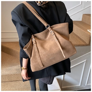 Detail of a brown leather tote bag showing the textured finish and buckle strap