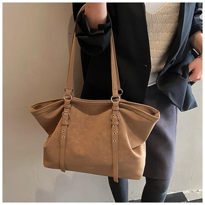 Detail view of large camel brown tote bag with decorative metal eyelet straps and long handles