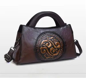 Detail view of vintage embossed pattern on brown leather half-moon shoulder bag