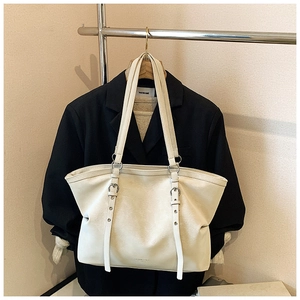 Detail of minimalist cream tote bag with silver adjustable buckles and long straps