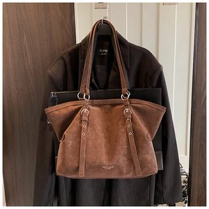 Détail du sac cabas en cuir marron vintage avec bandoulières réglables et logo doré