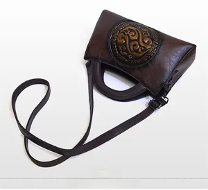 Detailed top view of retro dark brown leather bag with embossed round pattern and bronze hardware