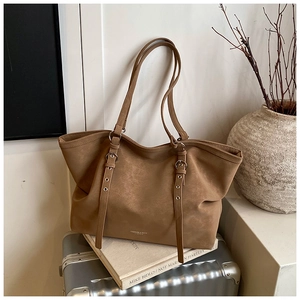 Close-up of khaki faux leather tote bag showing adjustable strap with silver buckles