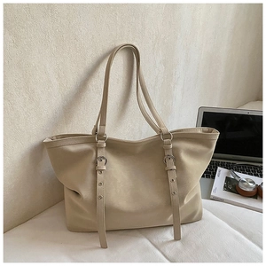 Detail of beige tote bag showing metal buckles, adjustable straps and large capacity
