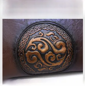 Macro detail of brown leather bag featuring vintage embossed circular totem pattern
