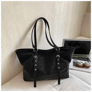 Detail of premium black tote bag with matte texture, gold logo, and stylish metal buckles