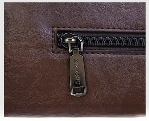 Detail of premium brown textured leather bag with polished XIN SHU metal zipper puller