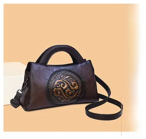 Close-up of vintage brown leather handbag with traditional round embossed cloud pattern