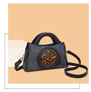 Detail of vintage embossed leather handbag with ethnic pattern and metallic hardware